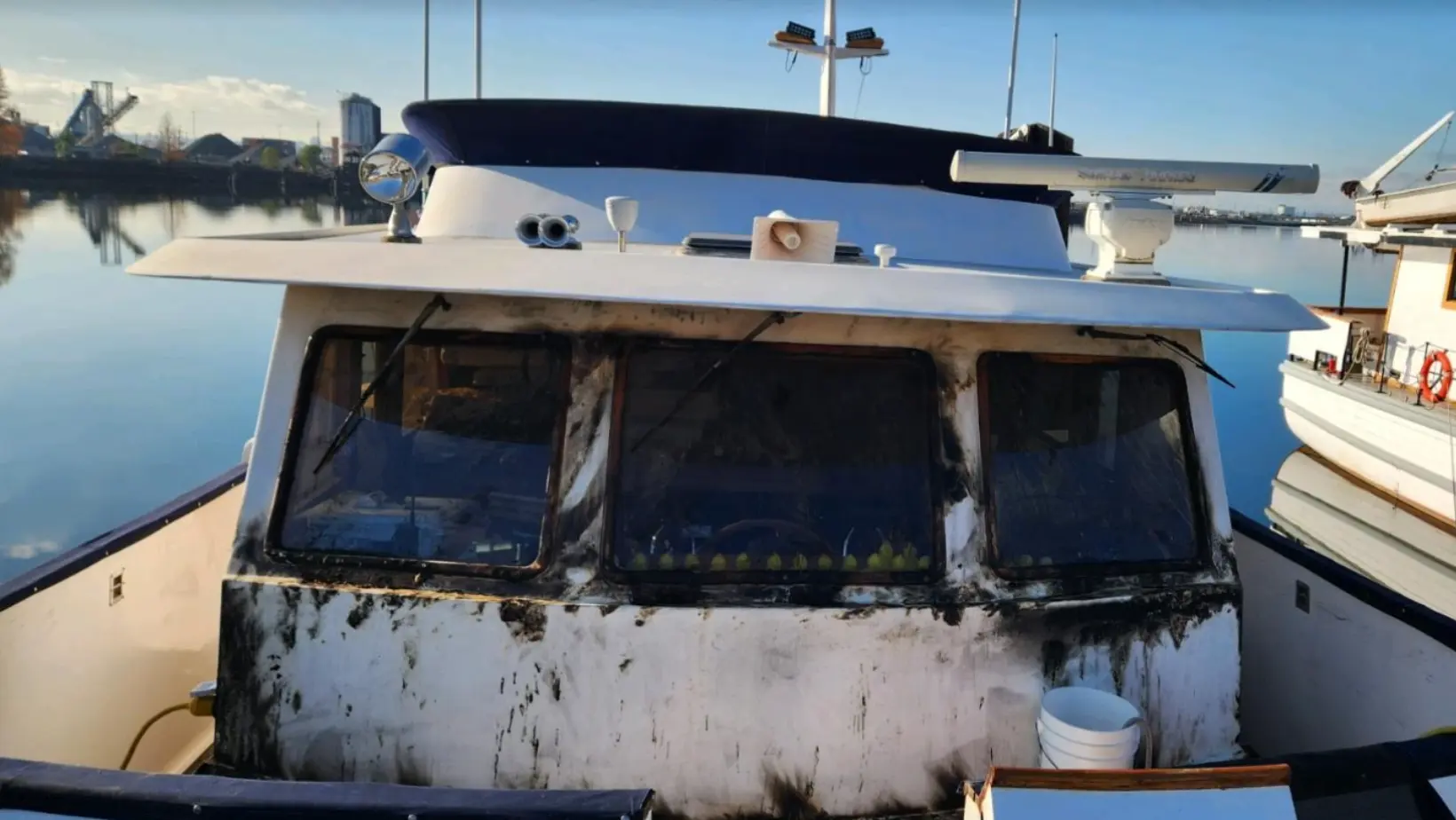 Fire-damaged window frame and canvas covering on a yacht at South Tacoma Marina, caused by an arcing shore power cord